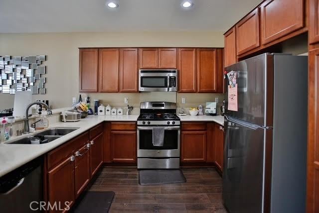 kitchen featuring dark wood-type flooring, recessed lighting, light countertops, a sink, and appliances with stainless steel finishes