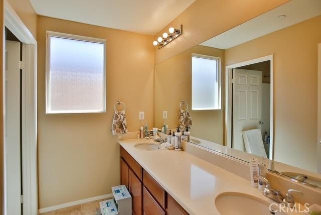 bathroom featuring double vanity, baseboards, and a sink