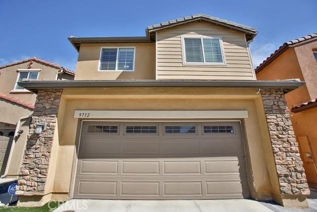 view of front facade with an attached garage, driveway, and stone siding