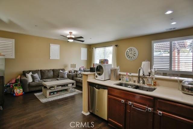 kitchen featuring a sink, dishwasher, light countertops, visible vents, and dark wood-style floors