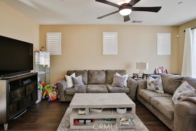living room featuring ceiling fan, dark wood-style flooring, and visible vents