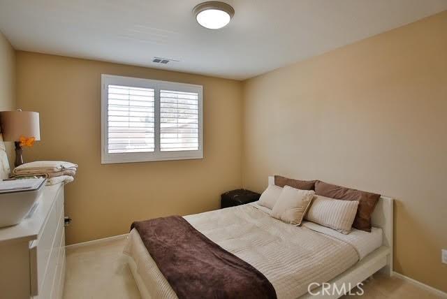 bedroom with baseboards, visible vents, and light colored carpet