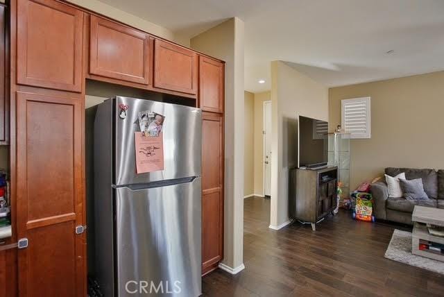 kitchen featuring freestanding refrigerator, baseboards, open floor plan, brown cabinets, and dark wood finished floors