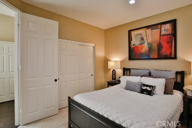 bedroom with recessed lighting, light colored carpet, and a closet