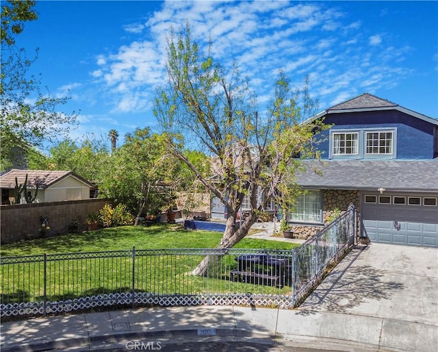 traditional home featuring concrete driveway, fence private yard, stone siding, a front yard, and a garage