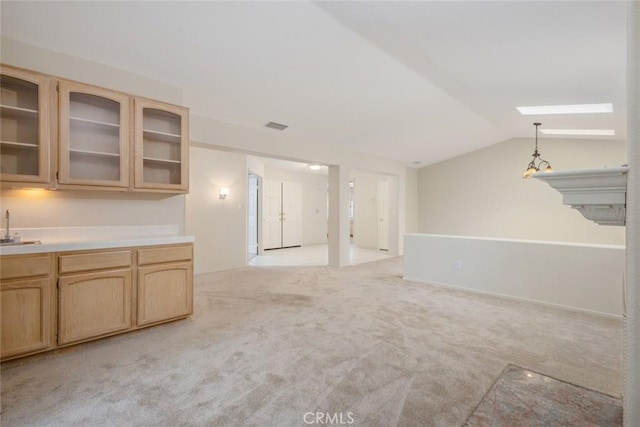 unfurnished living room with lofted ceiling, a sink, light colored carpet, and visible vents