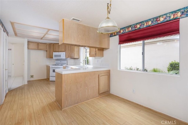 kitchen with white appliances, light countertops, light wood-type flooring, visible vents, and a peninsula