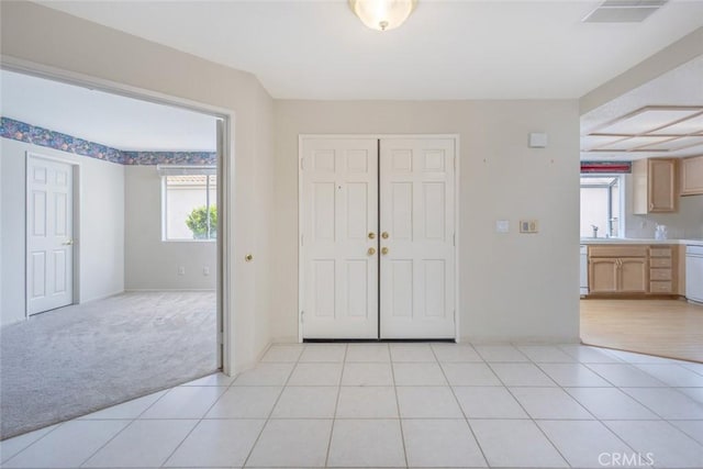 entrance foyer with light tile patterned flooring, visible vents, a wealth of natural light, and light colored carpet