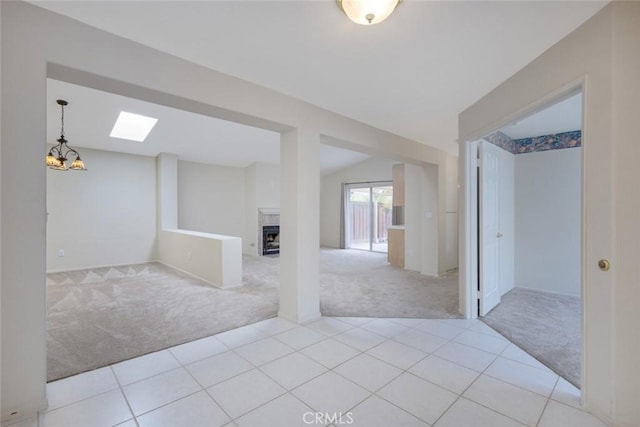interior space with light tile patterned floors, an inviting chandelier, light carpet, and a fireplace