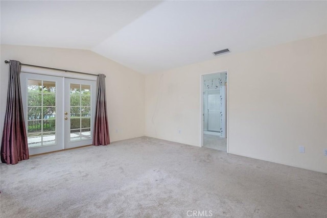 spare room with lofted ceiling, french doors, carpet, and visible vents