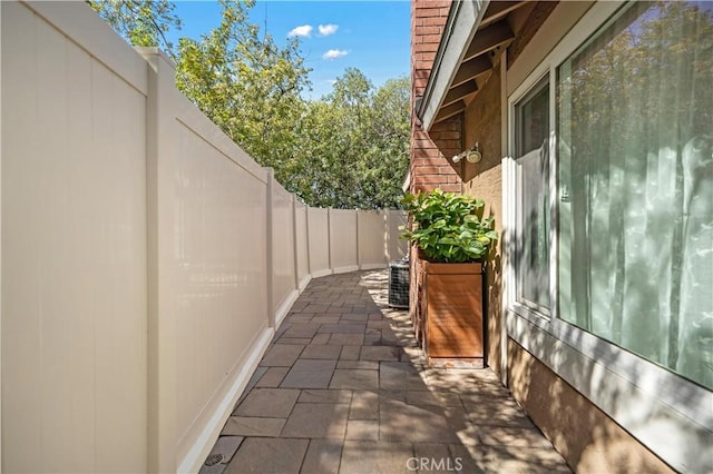 view of property exterior with a patio, central AC unit, and fence