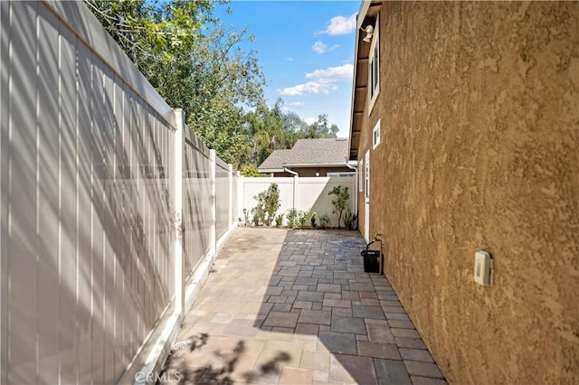 view of side of property with a patio, stucco siding, and a fenced backyard