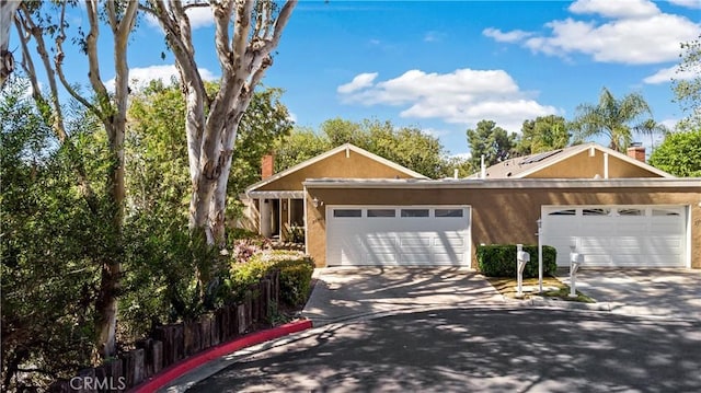 view of front of house featuring concrete driveway, stucco siding, and a chimney