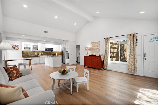 living area with high vaulted ceiling, beamed ceiling, light wood-style flooring, visible vents, and recessed lighting