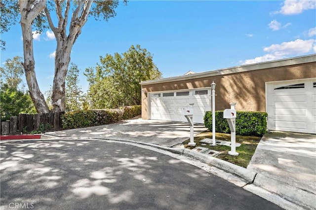 garage featuring driveway and fence