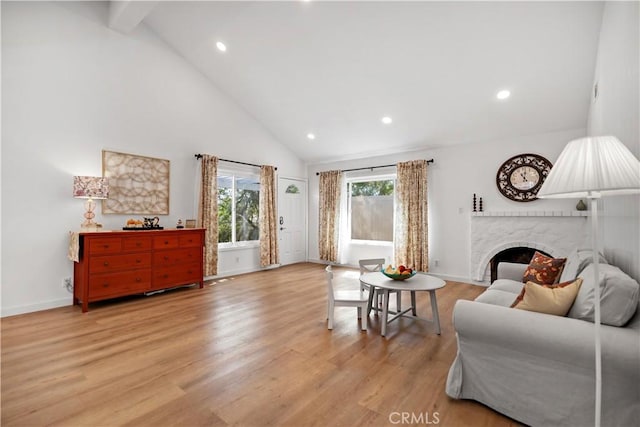 living room with high vaulted ceiling, a fireplace, light wood-style floors, and recessed lighting
