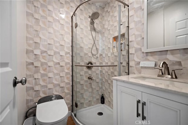 full bathroom with toilet, tasteful backsplash, vanity, and a stall shower