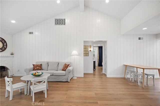 living room with a fireplace, visible vents, lofted ceiling with beams, and wood finished floors