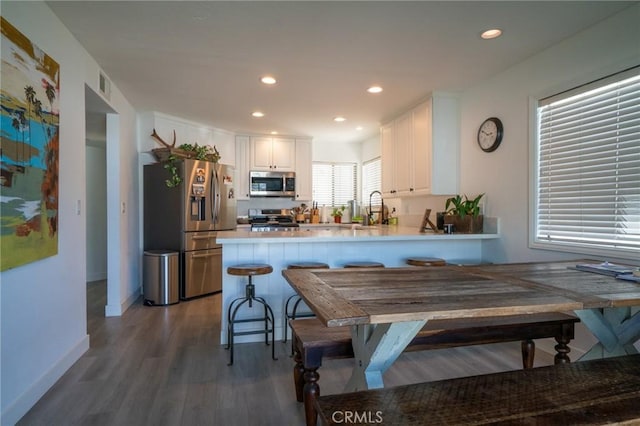 207 Knox St, Costa Mesa, CA 92627 - kitchen with a peninsula, white cabinets, visible vents, wood finished floors, and stainless steel appliances