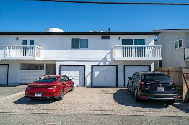 207 Knox St, Costa Mesa, CA 92627 - view of property featuring an attached garage, fence, a balcony, stucco siding, and driveway
