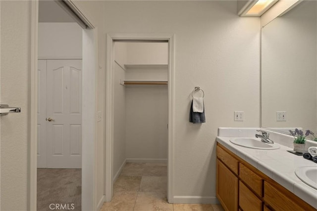 bathroom featuring a closet, baseboards, a sink, double vanity, and tile patterned flooring