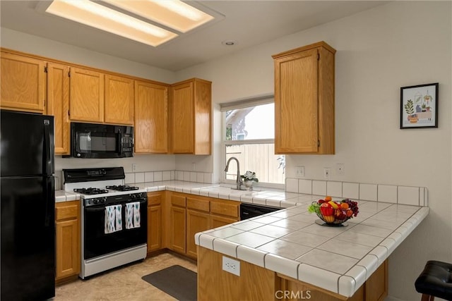 kitchen with a sink, black appliances, tile countertops, and a peninsula