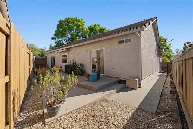 back of house featuring a patio area, stucco siding, central AC unit, and a fenced backyard