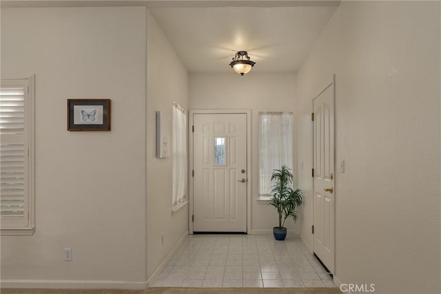 foyer featuring baseboards and light tile patterned flooring