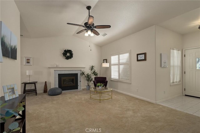 living room featuring ceiling fan, carpet, visible vents, vaulted ceiling, and a tile fireplace