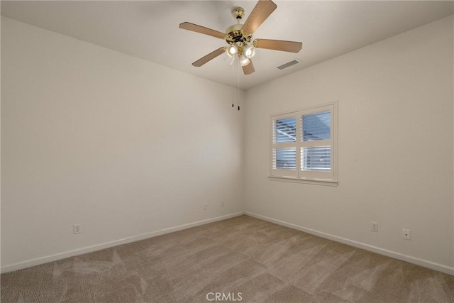 spare room with light colored carpet, baseboards, a ceiling fan, and visible vents