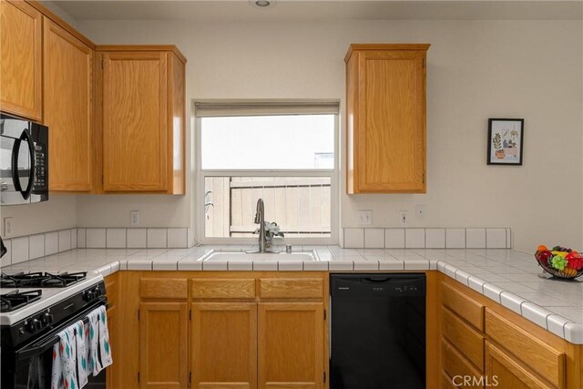 kitchen with light countertops, a sink, and black appliances