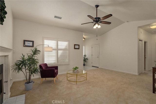 living area with visible vents, ceiling fan, a fireplace with flush hearth, light colored carpet, and lofted ceiling