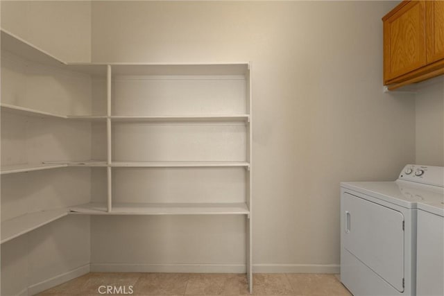 washroom with washer and dryer, light tile patterned floors, baseboards, and cabinet space