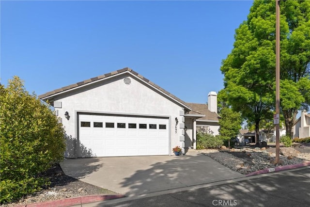 ranch-style house with a tiled roof, stucco siding, a chimney, a garage, and driveway