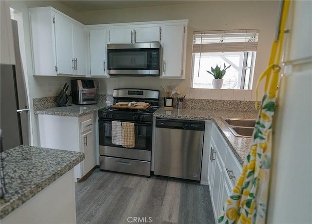 1094 Award Dr, Colton, CA 92324 - kitchen featuring appliances with stainless steel finishes, wood finished floors, a sink, white cabinetry, and light stone counters