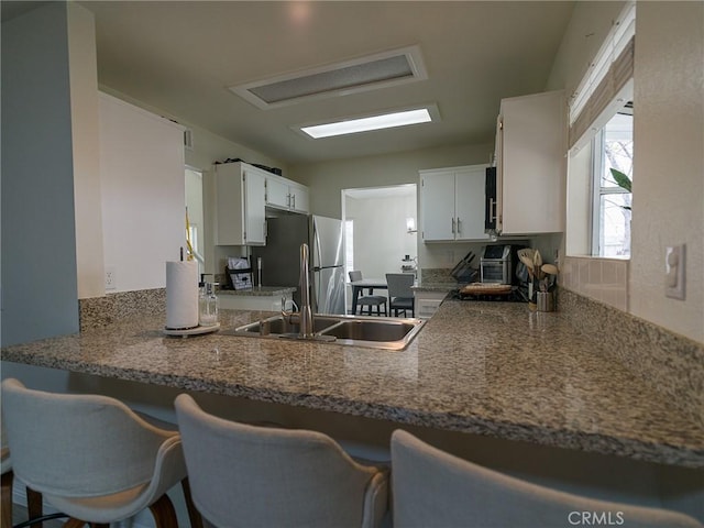 1094 Award Dr, Colton, CA 92324 - kitchen featuring freestanding refrigerator, a peninsula, white cabinetry, and a sink