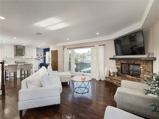 living area featuring dark wood-style flooring, visible vents, recessed lighting, and a fireplace