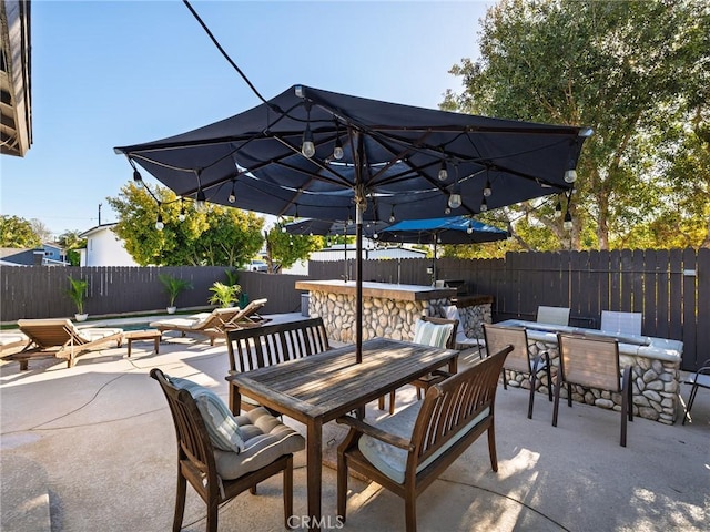 view of patio / terrace featuring a fenced backyard, outdoor dining space, and outdoor dry bar