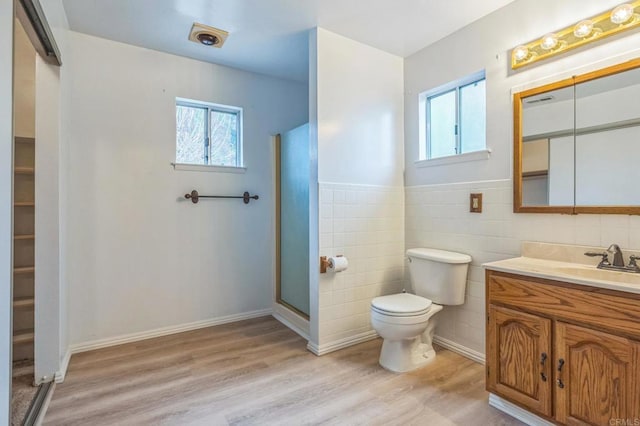 full bathroom featuring wood finished floors, a healthy amount of sunlight, toilet, and tile walls