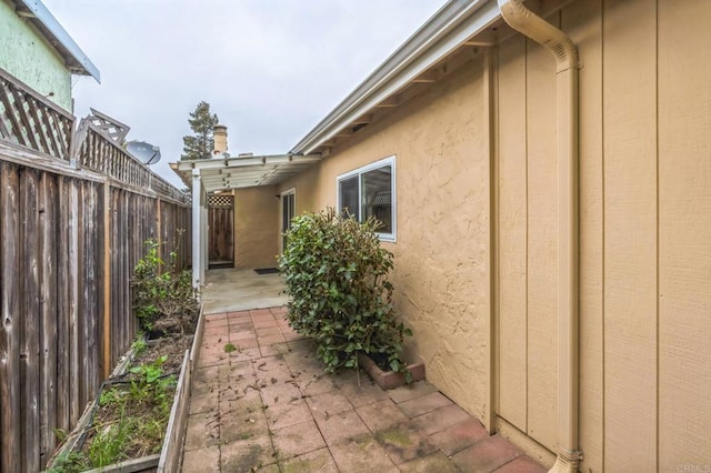 view of home's exterior with stucco siding, a patio, and fence