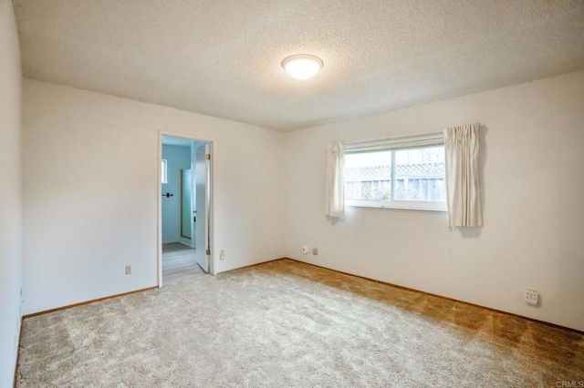 carpeted empty room with baseboards and a textured ceiling