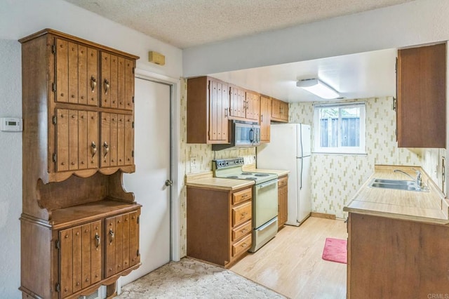 kitchen featuring white electric range oven, a sink, light wood-style floors, light countertops, and stainless steel microwave
