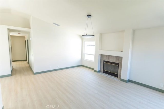 unfurnished living room featuring light wood-type flooring, a fireplace, baseboards, and visible vents