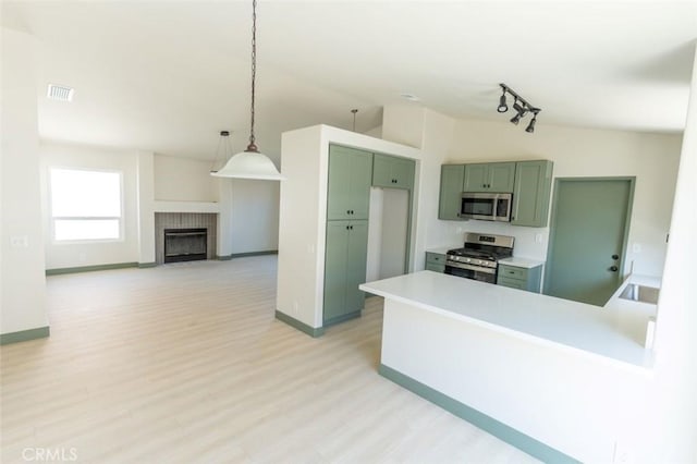 kitchen featuring a peninsula, green cabinetry, light wood-style floors, visible vents, and stainless steel appliances