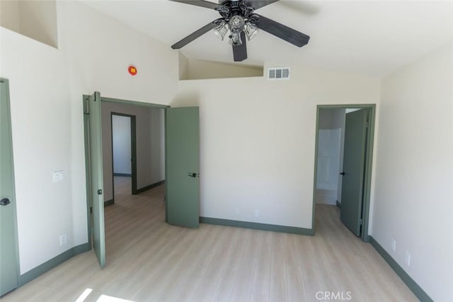 unfurnished bedroom with light wood finished floors, baseboards, lofted ceiling, and visible vents