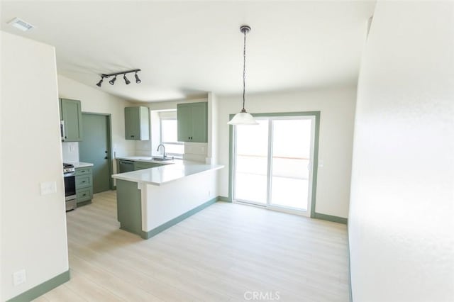 kitchen with green cabinetry, a peninsula, light wood-type flooring, and gas stove