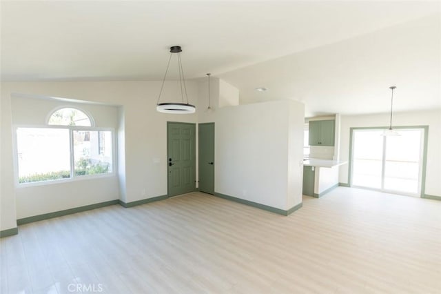 unfurnished living room featuring light wood finished floors, baseboards, and vaulted ceiling