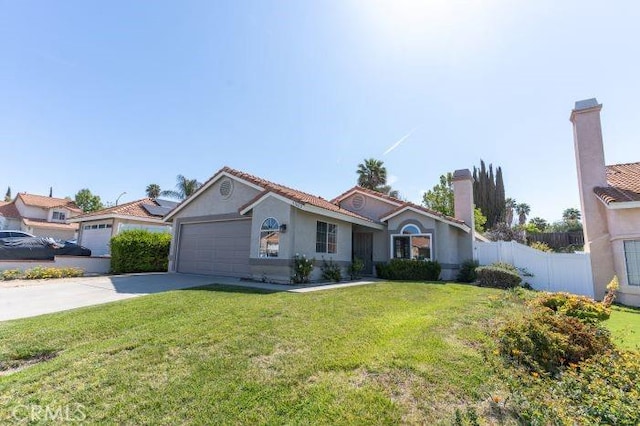 mediterranean / spanish-style house featuring concrete driveway, a garage, fence, and a front lawn