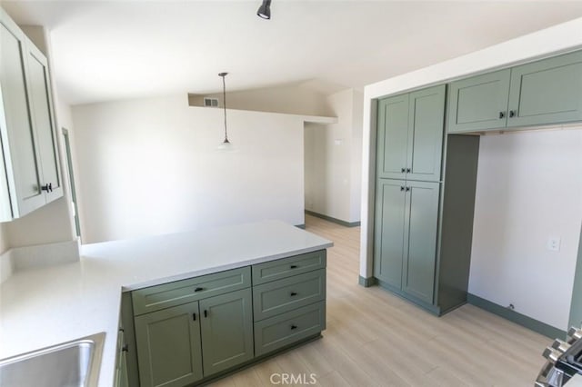 kitchen with green cabinetry, light wood-type flooring, a peninsula, pendant lighting, and lofted ceiling