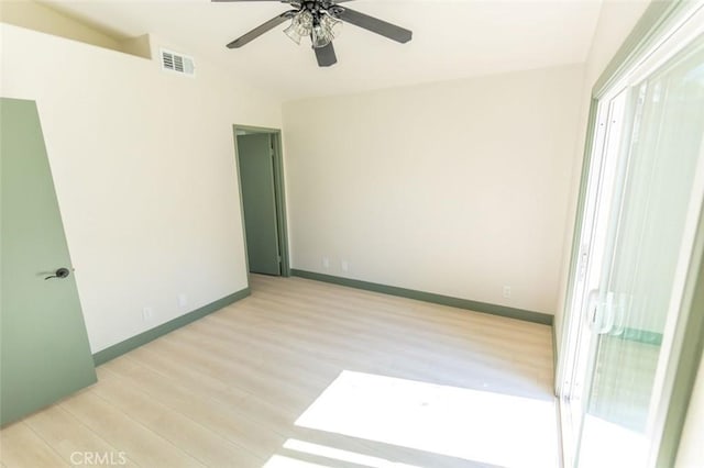 spare room featuring light wood-type flooring, vaulted ceiling, a ceiling fan, and visible vents